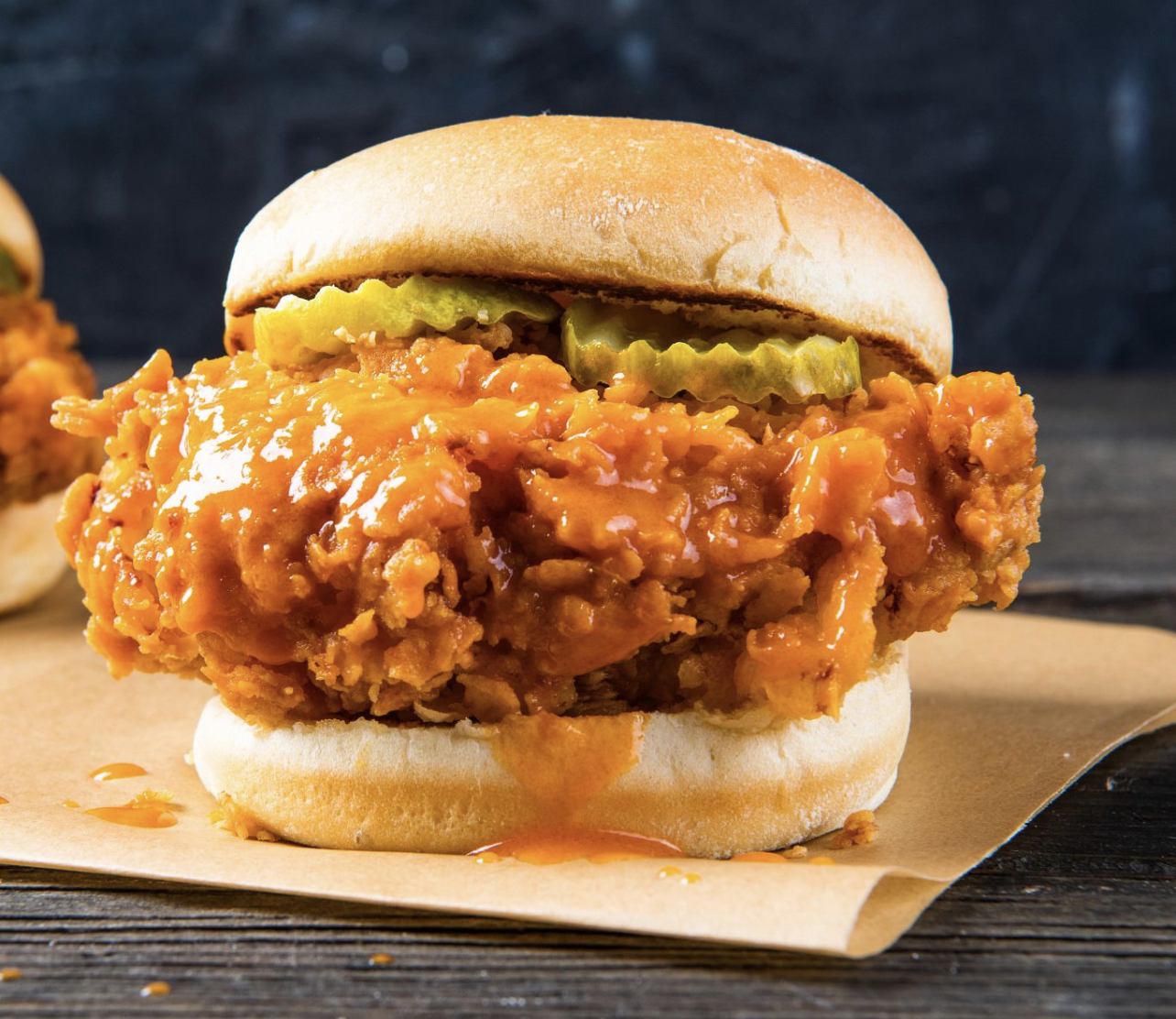 Crispy fried chicken sandwich glazed in hot honey sauce with pickles on a toasted bun