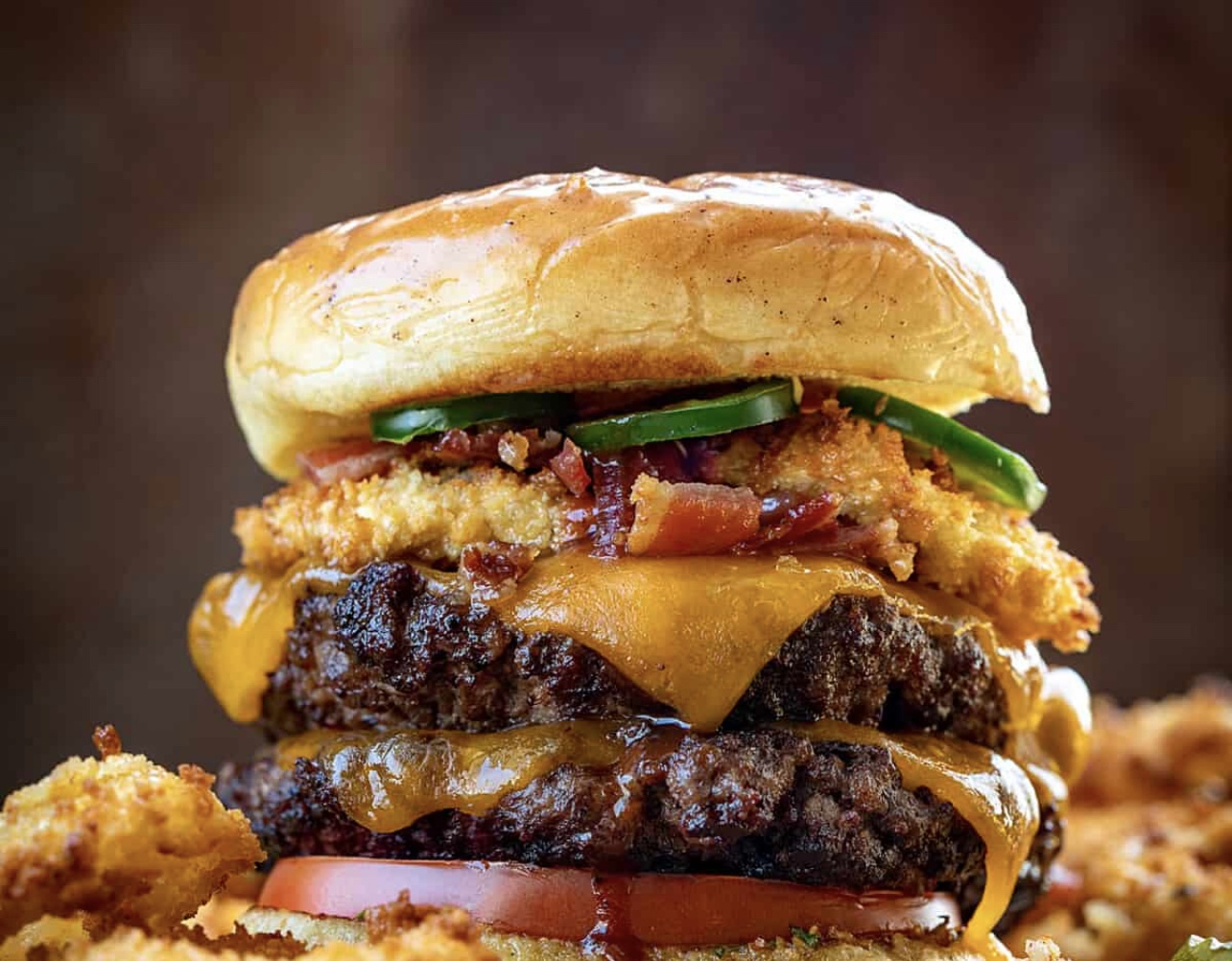 Double cheeseburger stacked with bacon, hot peppers and crispy onions on a brioche bun