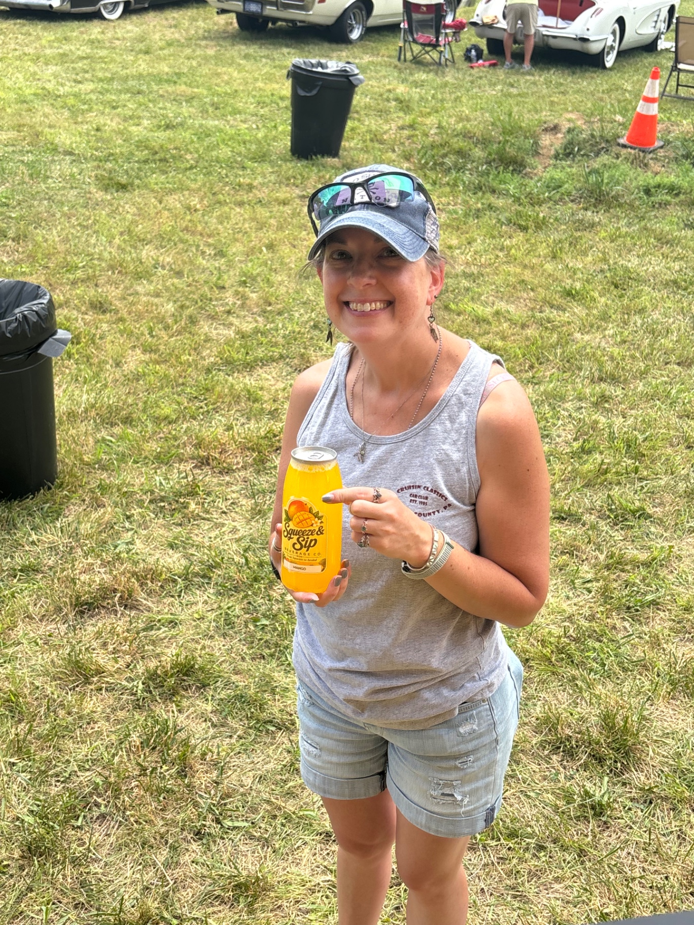 Smiling customer pointing at her mango Squeeze & Sip lemonade at a Mallie's Burgers car show setup