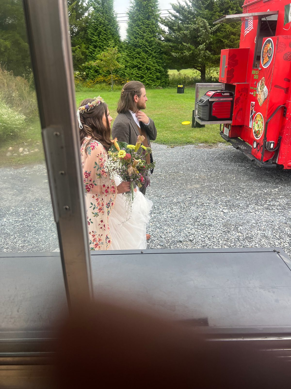 Bride and groom standing outside the food truck at their wedding reception