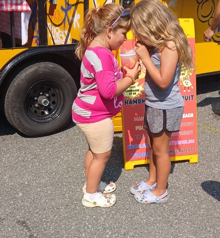 Two kids sharing fresh-squeezed lemonade beside the Mallie's Burgers truck