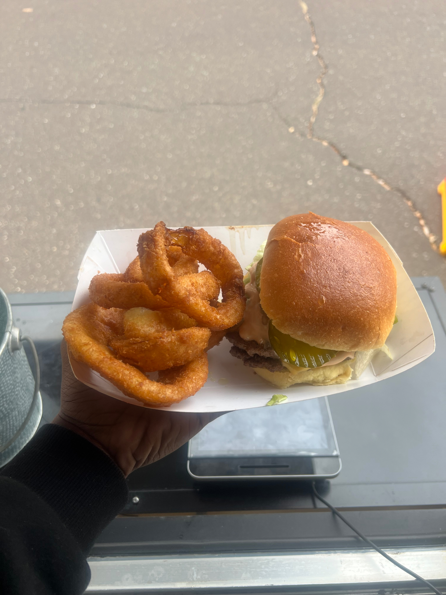 Cheeseburger with pickles served alongside golden onion rings on a paper tray