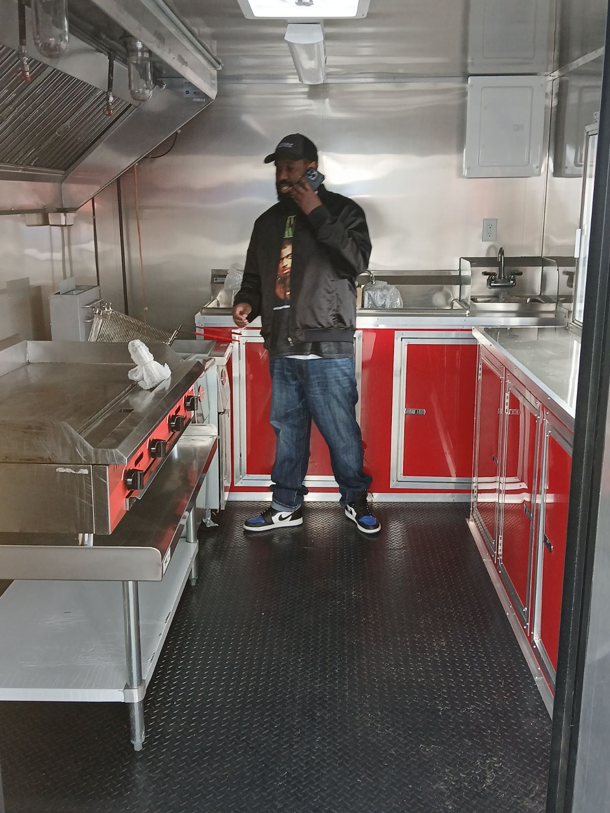 Chef Jamal inside the Mallie's Burgers food truck kitchen, checking an order on his phone