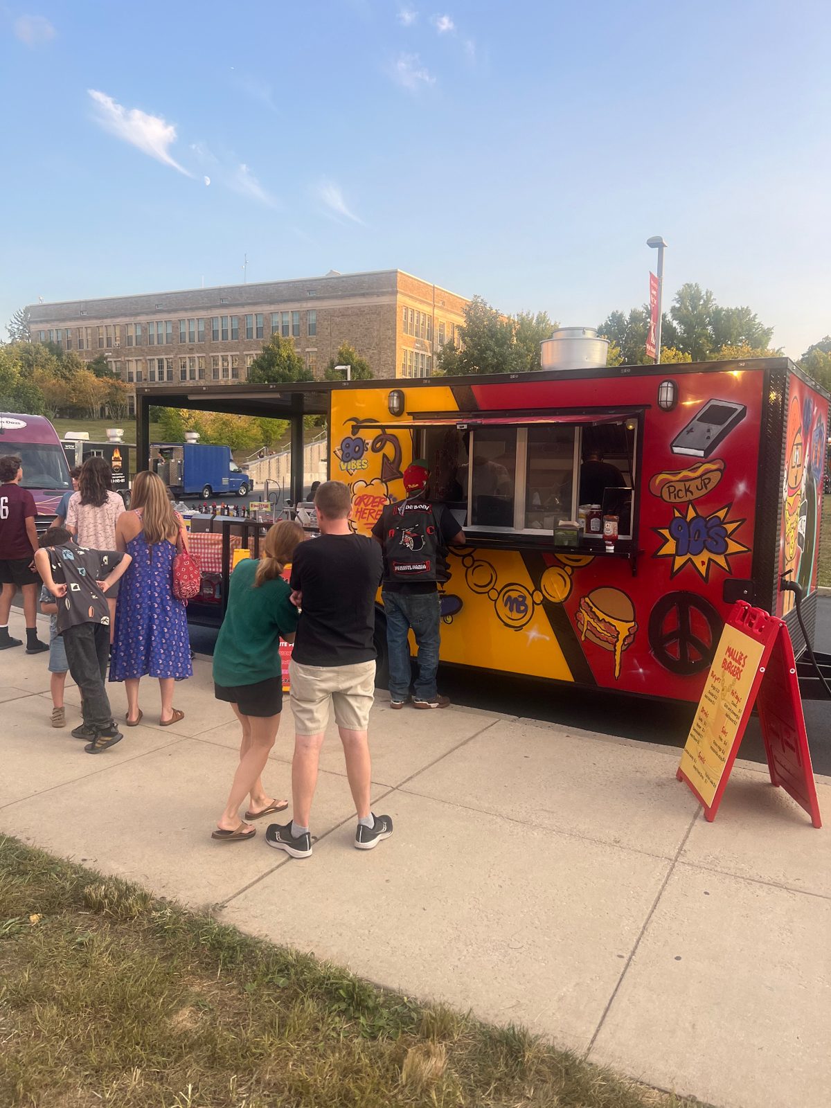 Mallie's Burgers food truck parked on a school campus with guests lined up to order