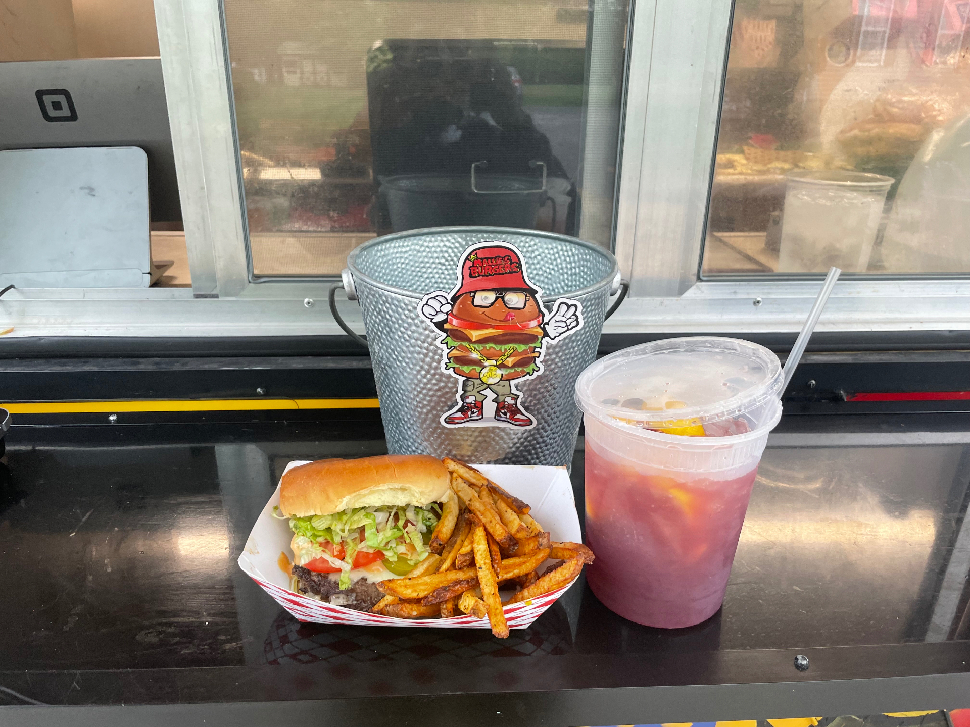 Burger and fries tray next to a cup of fresh-squeezed strawberry lemonade at the truck window