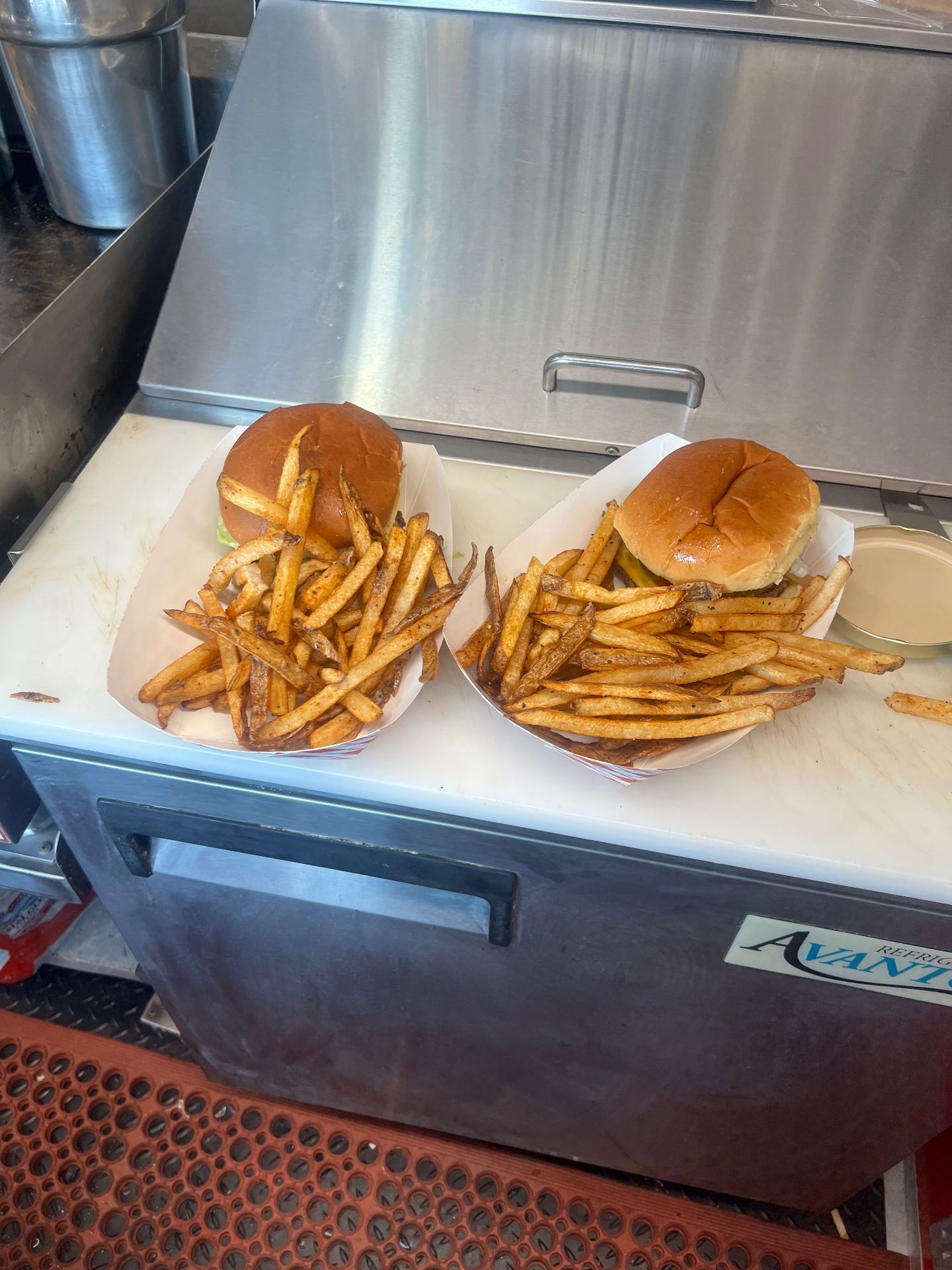 Two smashburgers in paper trays piled with hand-cut seasoned fries inside the food truck