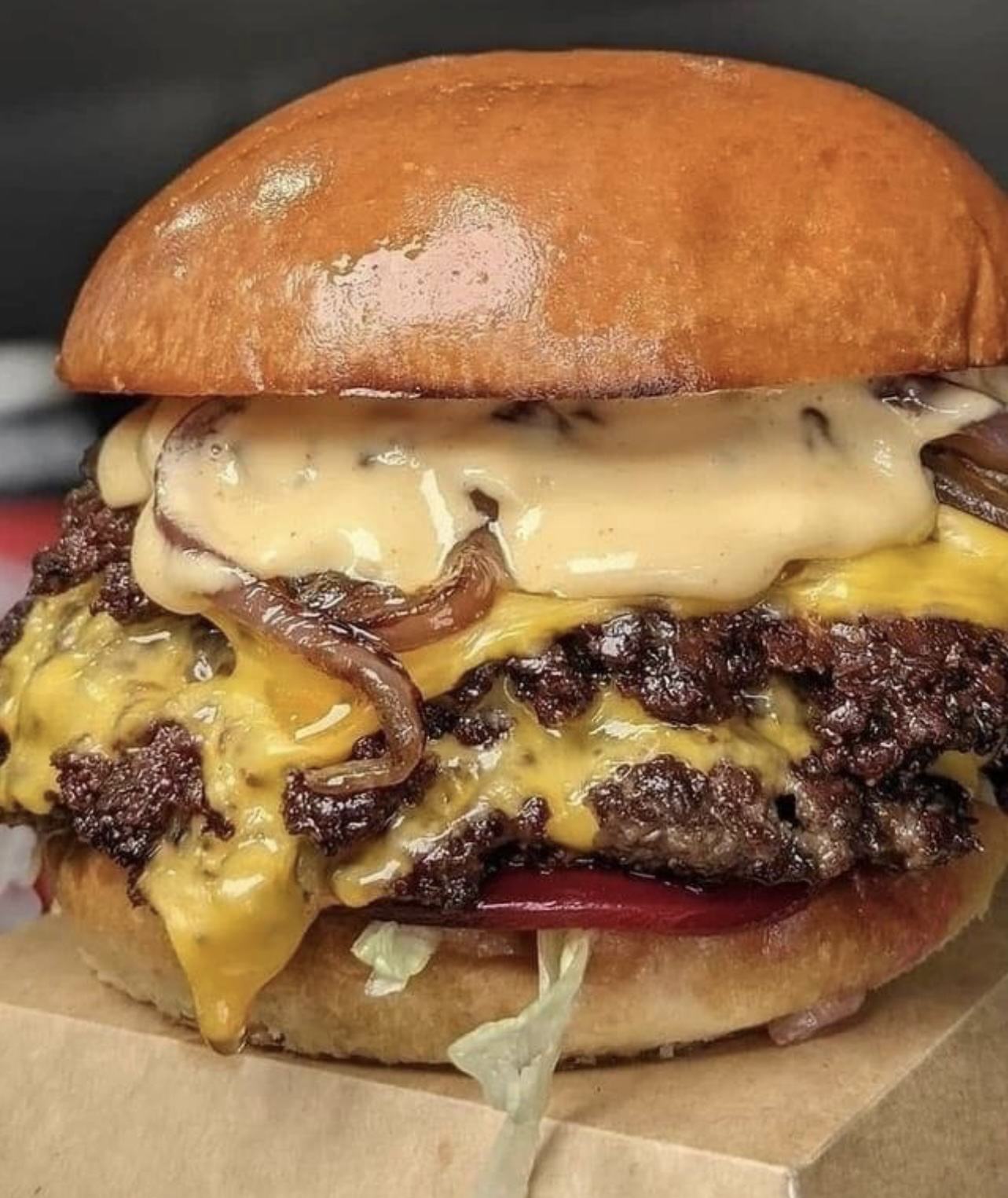 Double smashburger on a brioche bun with melted cheese, caramelized onions, lettuce, tomato and house sauce