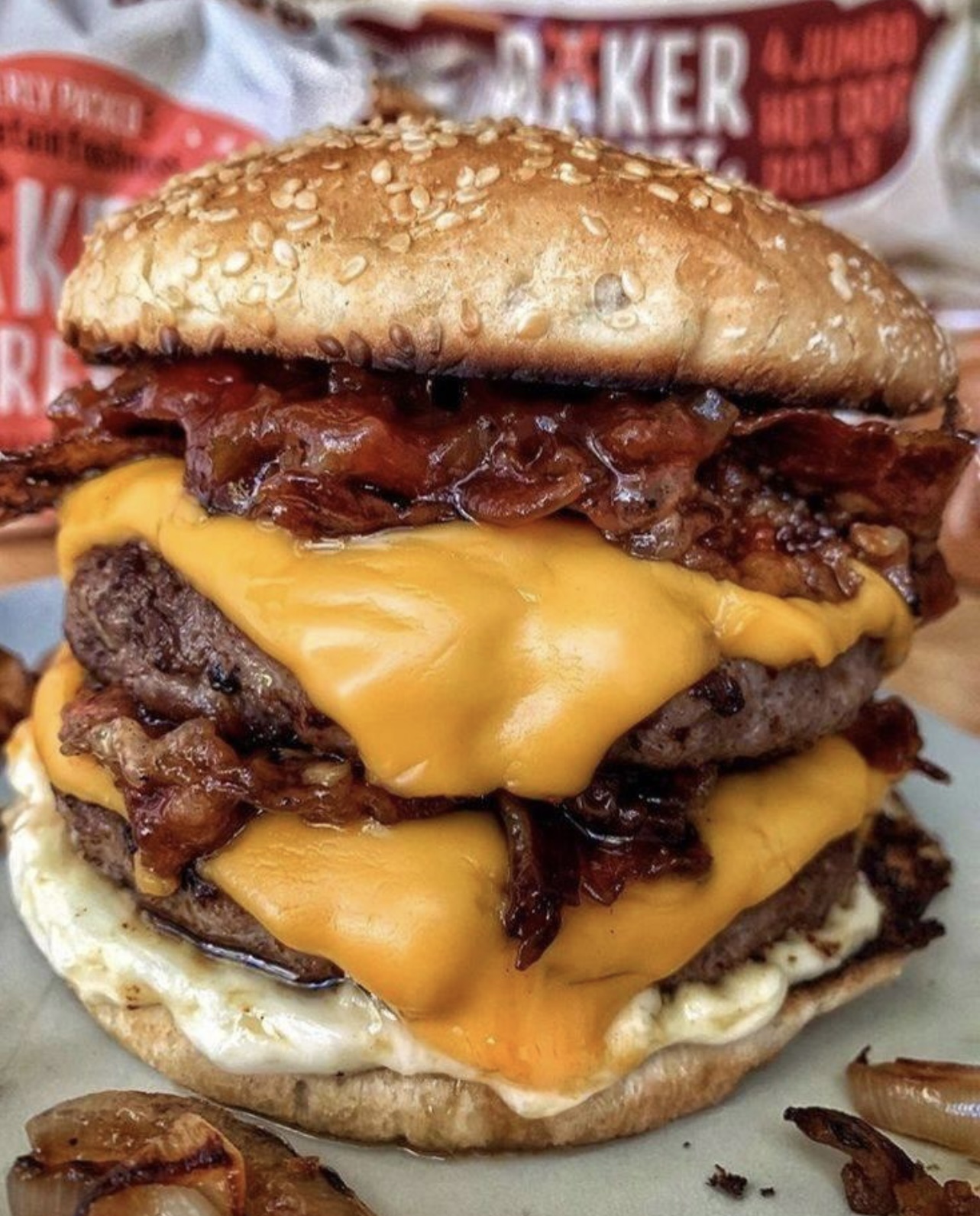 Double smashburger stacked with American cheese, candied bacon and grilled onions on a toasted sesame bun