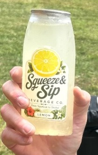 Close-up of the Squeeze & Sip classic lemon label on a bottle held by a guest at a Pennsylvania car show served by Mallie's Burgers