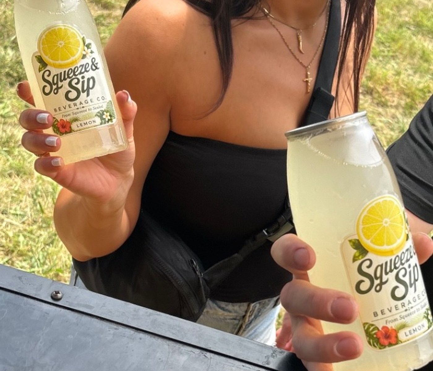 Close-up of two guests toasting cans of Squeeze & Sip fresh-squeezed lemonade, label front and center, at a Mallie's Burgers catering event